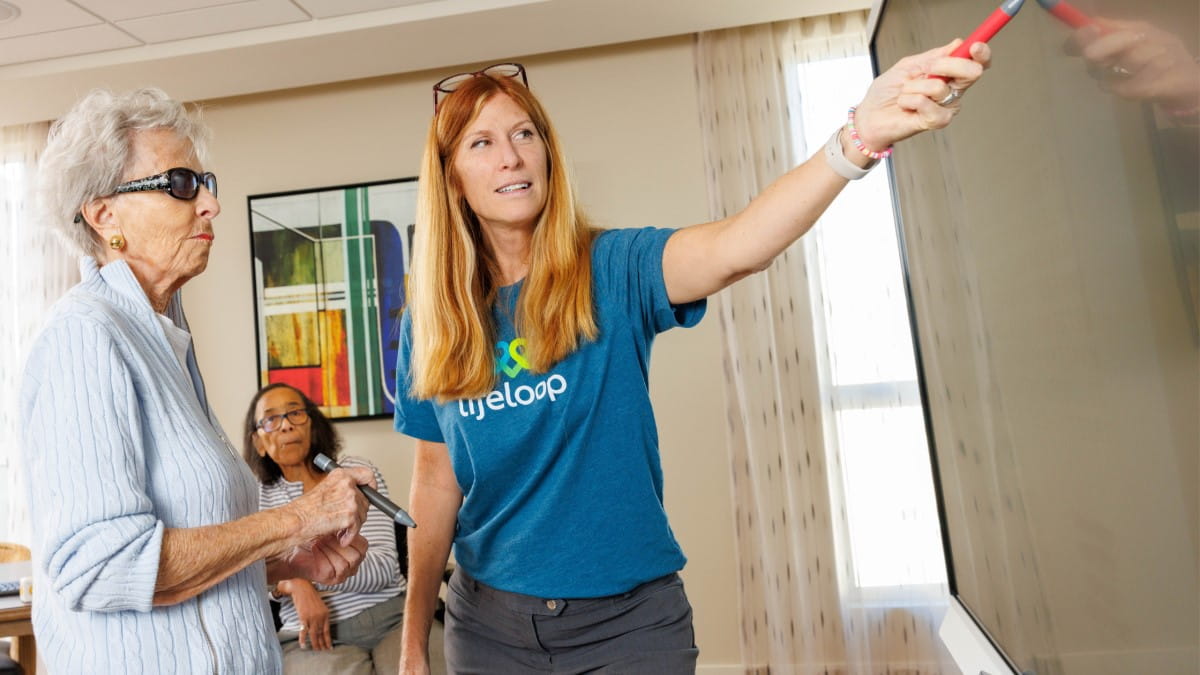 A senior and caregiver interacting with digital content on a SMART Board.
