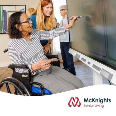 A senior resident with her caregiver, interacting on a SMART Board using digital ink.
