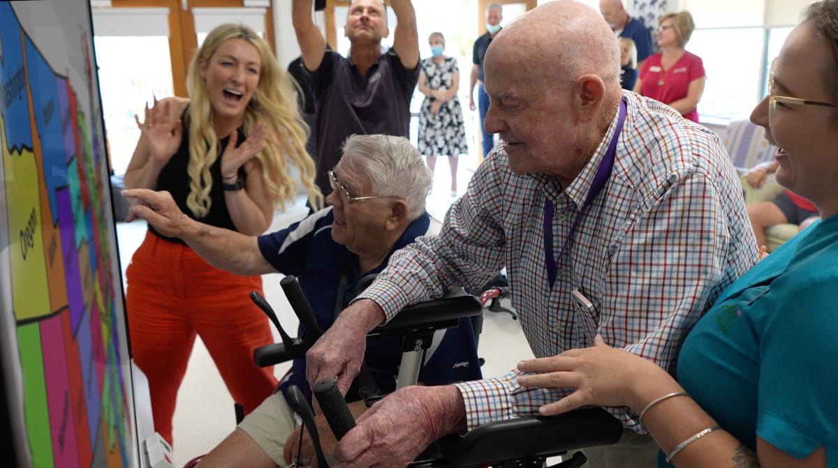 Senior care residents in a care home engaging with colorful activities on a SMART Board.